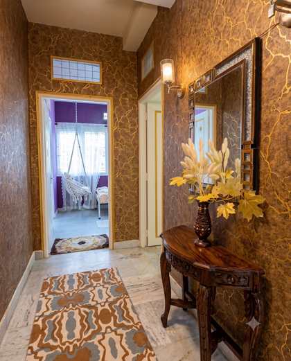 The gold corridor at Renu’z Homestay with a carved wooden console and mirror