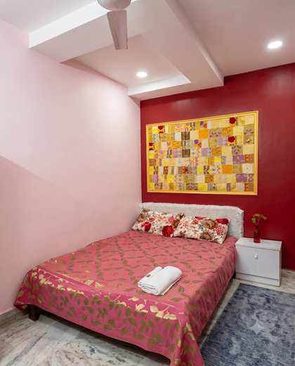The Crimson Room at Renu'z Homestay, with one crimson wall, one blush wall and a gold-framed patchwork panel above the bed