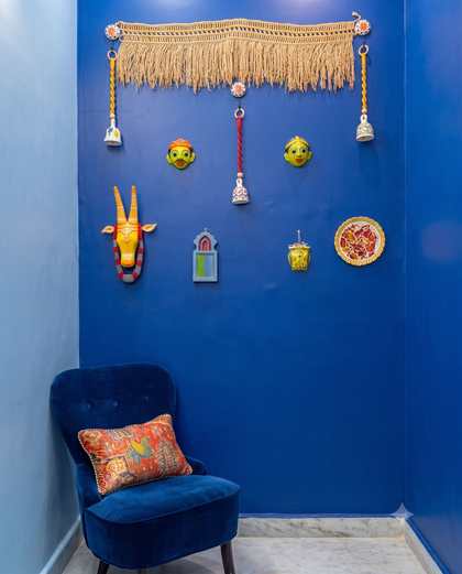 A cobalt blue wall at Renu’z Homestay hung with painted folk masks and brass bells